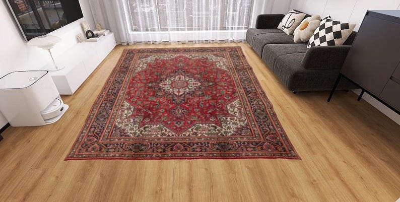May include: A rectangular, ornate red rug with a central medallion design and intricate border patterns. The rug features a rich color palette of red, cream, and dark accents, adding warmth to the room. The rug is placed on a wooden floor.