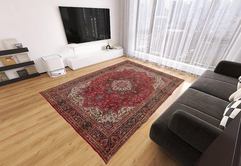 May include: A large, rectangular red Persian rug with an intricate floral pattern dominates a living room. The rug features a central medallion and detailed borders in shades of red, cream, and brown, adding warmth to the space.