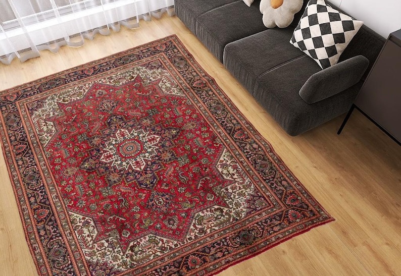 May include: A large, rectangular red Persian rug with an intricate floral pattern and a central medallion. The rug features a border with dark blue and cream accents, and is placed on a hardwood floor.