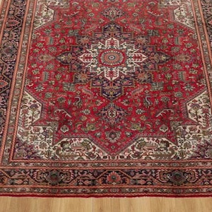 May include: A rectangular, red Persian rug with an intricate central medallion design and ornate borders. The rug features a complex pattern with cream, navy, and green accents. It is placed on a wooden floor.