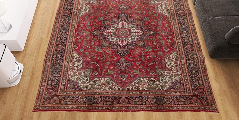 May include: A rectangular, red Persian rug with an intricate central medallion design and ornate borders. The rug features a complex pattern with cream, navy, and green accents. It is placed on a wooden floor.