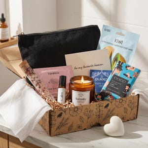 Könnte beinhalten: Eine Geschenkbox mit Artikeln zur Selbstpflege. Sie enthält eine schwarze Reißverschlusstasche, eine Kerze mit der Aufschrift "Serenity", eine Gesichtsmaske, einen Schokoriegel, eine Karte mit der Aufschrift "for my favourite human", ein Roll-on-Fläschchen "Calm" und eine herzförmige Seife.
