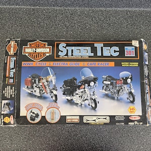 May include: A Steel Tec Harley-Davidson construction system box set featuring 545 parts to build three motorcycle models: a WWII cycle, Electra Glide, and cafe racer. The box includes a battery-powered motor, spring suspension, and four tools.