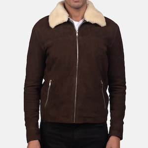 Può includere: Giacca in pelle scamosciata marrone con colletto in montone color crema. La giacca ha una chiusura con cerniera argentata e due tasche con cerniera. Giacca classica per il clima fresco. Il modello indossa una maglietta bianca sotto. La giacca è lunga circa 60 cm.