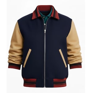 Puede incluir: Una chaqueta universitaria azul marino con mangas color canela, cuello a rayas rojas y negras y puños a juego. La chaqueta tiene una cremallera completa y dos bolsillos delanteros con ribete color canela. Se ve una camisa verde debajo.