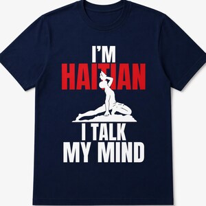 May include: Navy blue t-shirt featuring the text "I'M HAITIAN I TALK MY MIND" in white and red. A white graphic of a person in a yoga pose is centered on the shirt. The shirt is made of a soft material.