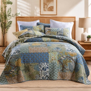 May include: A patchwork quilt with a mix of blue, green, and tan squares. The quilt features floral and geometric patterns. The bed is made with several pillows and a matching bedspread. The headboard is made of woven wood.