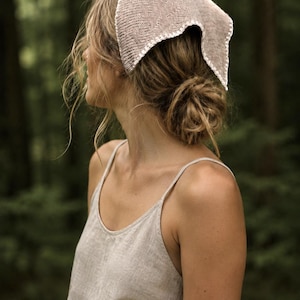 May include: A light beige triangular headscarf featuring a fine knit texture and a decorative white crocheted border edge. The headscarf is paired with a matching light beige sleeveless top with thin shoulder straps, creating a coordinated look.