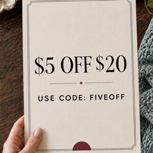 Może przedstawiać: Prostokątna karta w kolorze złamanej bieli z cienką czarną ramką, zawierająca napis $5 OFF $20 dużą czarną czcionką, małą bordową ikonę rombu oraz napis USE CODE: FIVEOFF mniejszą czarną czcionką, z bordowym p&oacute;łkolem u dołu.