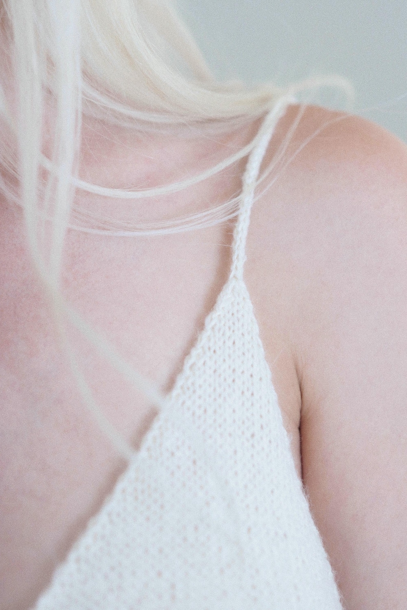 Knit camisole single knitting pattern. v-neck tank top knitting pattern. beginner knit singlet pattern. summer tank top knitting pattern with spaghetti straps. Easy cami knit pattern. Summer singlet top knitting pattern. Knitted singlet. Woman wears a basic knitted camisole that was knit in white yarn using this knitting pattern