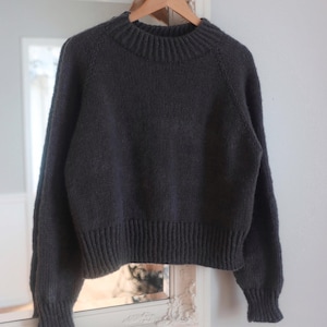 Women's cropped raglan sweater knitting pattern, oversized seamless top-down pullover in worsted weight yarn, beginner knit jumper PDF instant download. easy knit sweater pattern, beginner knit raglan sweater. Flat lay of cropped crewneck sweater in worsted weight yarn, seamless raglan knitting pattern for women