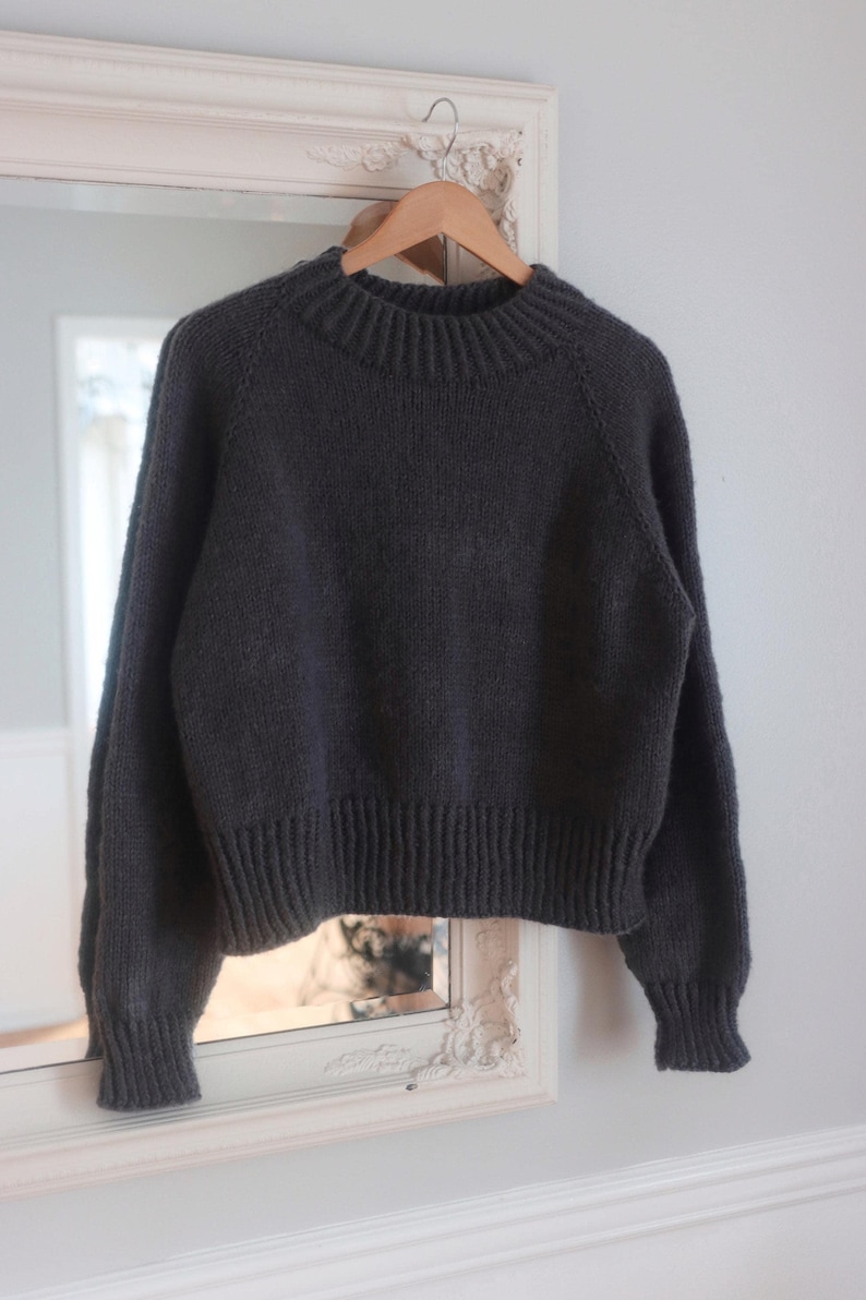 Women's cropped raglan sweater knitting pattern, oversized seamless top-down pullover in worsted weight yarn, beginner knit jumper PDF instant download. easy knit sweater pattern, beginner knit raglan sweater. Flat lay of cropped crewneck sweater in worsted weight yarn, seamless raglan knitting pattern for women