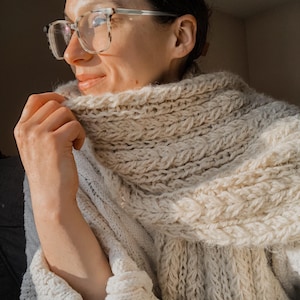 Chunky wrap scarf draped on table, warm knit pattern materials and finished project. easy scarf knitting pattern, chunky knit scarf pattern. Warm wrap scarf knitting pattern, oversized women's knit scarf in worsted weight yarn, easy beginner cozy knit wrap PDF instant download. women knit scarf pattern, easy knitting pattern. rectangle scarf knit pattern. chunky heart scarf knit pattern