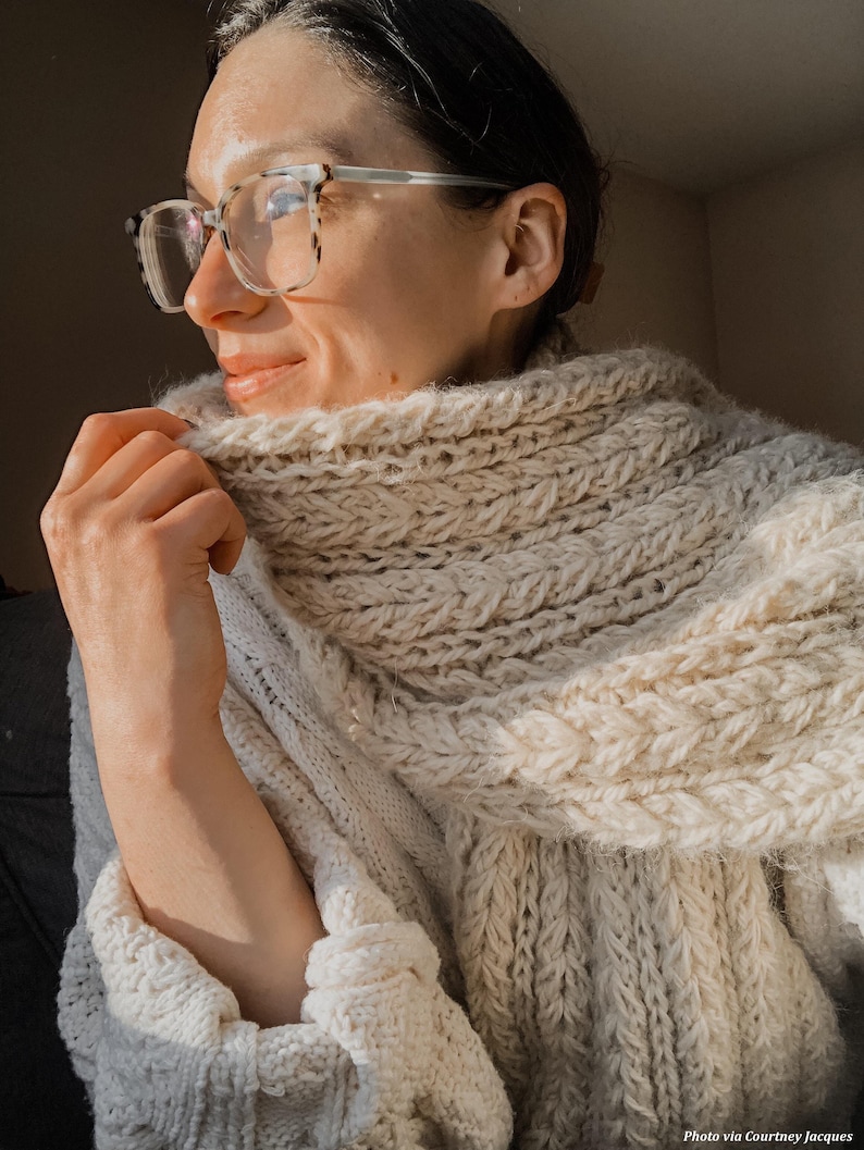 Chunky wrap scarf draped on table, warm knit pattern materials and finished project. easy scarf knitting pattern, chunky knit scarf pattern. Warm wrap scarf knitting pattern, oversized women's knit scarf in worsted weight yarn, easy beginner cozy knit wrap PDF instant download. women knit scarf pattern, easy knitting pattern. rectangle scarf knit pattern. chunky heart scarf knit pattern