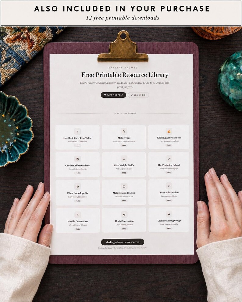 May include: A dark purple clipboard holding a white document titled Free Printable Resource Library. The document features a grid of twelve rectangular buttons with icons and text labels for various knitting and crochet reference guides.