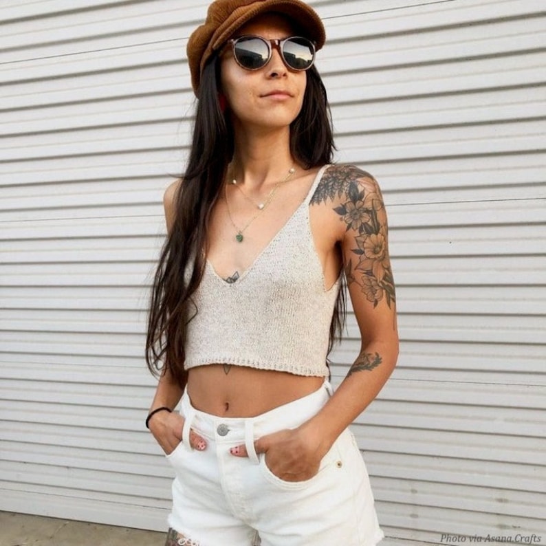 . The v-neck tank top features spaghetti straps and classic knit stitches. The lightweight cami is easy to knit and a great fashion top for summer. Woman wears knitted camisole, easy knitting pattern by Darling Jadore