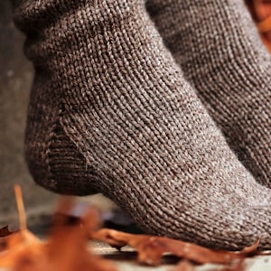 Closeup photo of cozy knitted socks, THe Beginner Socks, knit using the knitting pattern. This pair of knit socks were knitted using brown worsted weight yarn and the socks are warm, thick, and cozy.
[easy knit sock pattern, knitted socks]