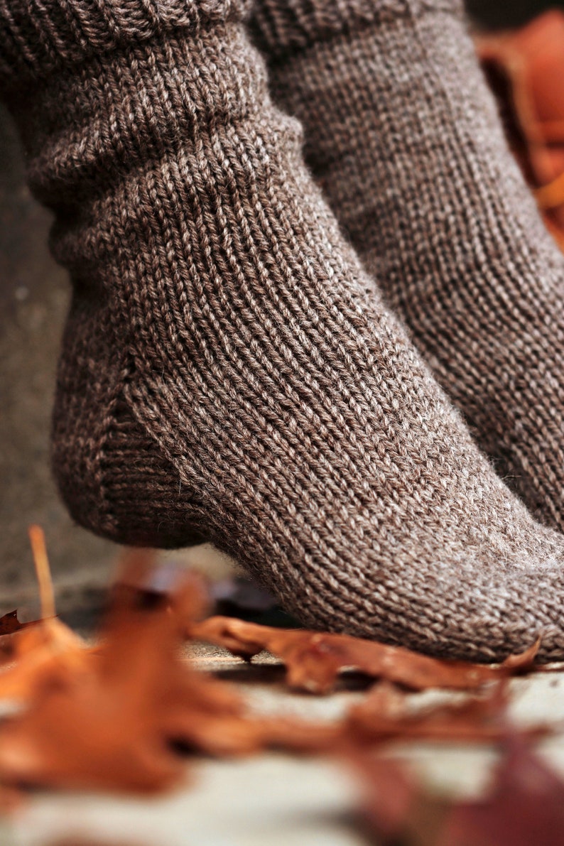 Closeup photo of cozy knitted socks, THe Beginner Socks, knit using the knitting pattern. This pair of knit socks were knitted using brown worsted weight yarn and the socks are warm, thick, and cozy.
[easy knit sock pattern, knitted socks]