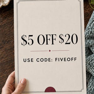 May include: A rectangular off-white card with a thin black border featuring the text $5 OFF $20 in large black font, a small maroon diamond icon, and the text USE CODE: FIVEOFF in smaller black font, with a maroon semi-circle at the bottom.