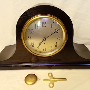 May include: A white ceramic mug with a black handle and the text "But First, Coffee" in a black, handwritten-style font. The mug is on a white surface.