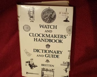 Puede incluir: Un libro de tapa dura blanco titulado Watch and Clockmakers' Handbook Dictionary and Guide de Britten. La portada presenta ilustraciones en tinta negra de varias herramientas de relojería y mecanismos de reloj, con una pequeña etiqueta de precio blanca.