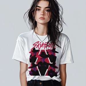 May include: White t-shirt featuring a graphic design with the text "Sajaton" in red and a group of figures wearing black hats. The design is set against a white background.