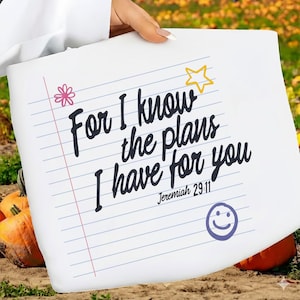 K&ouml;nnte beinhalten: Eine wei&szlig;e Tragetasche mit einem linierten Notizpapier-Design und dem schwarzen Text For I know the plans I have for you Jeremiah 29:11. Das Design enth&auml;lt eine rosa Blume, einen gelben Stern und ein violettes Smiley-Symbol auf der Vorderseite.