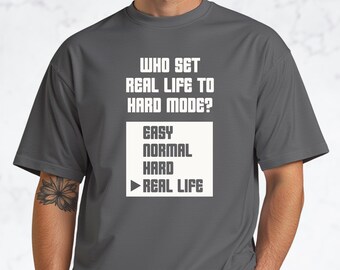 誰が現実をハードモードにしたのかTシャツ｜面白いゲーマーの格言Tシャツ