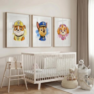 May include: Three framed watercolor prints featuring cartoon dog characters in hats and uniforms. The prints are displayed above a white crib in a nursery setting. The characters are in yellow, blue, and pink, with watercolor backgrounds.