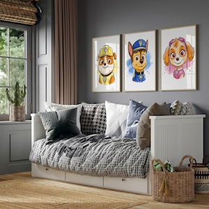 May include: Three framed watercolor prints of cartoon dogs in uniforms hang above a daybed. The prints feature a yellow, blue, and pink color scheme. The daybed has a checkered blanket, pillows, and a white frame. A woven basket sits in front.