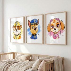 May include: Three framed watercolor prints featuring characters from the Paw Patrol series. Each print showcases a different puppy character with vibrant colors and a watercolor background. The prints are displayed above a wooden crib.