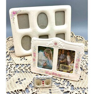 May include: A large cream-colored ceramic multi-photo frame with a crackle glaze and pink floral accents, a smaller rectangular double-photo frame with pink and blue floral details, and a tiny ceramic double-photo frame with red heart motifs.