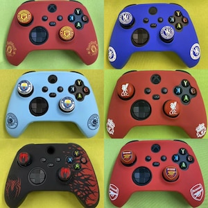 Può includere: Controller Xbox di vari colori, tra cui rosso, blu e nero. Ogni controller presenta loghi e design di squadre di calcio come Manchester United, Chelsea e Liverpool. Design moderno per il gaming.