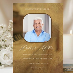 May include: A memorial card with a photo of a smiling man in a blue shirt. The card has a gold and brown background with the text "Celebrating the Life of Robert Miller" and memorial details. A white flower and candle are in the background.