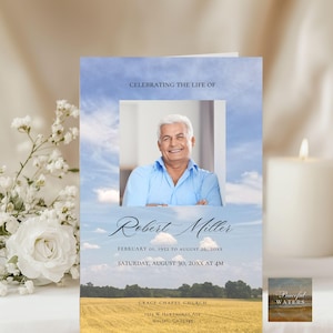 May include: A memorial card featuring a photograph of a man in a blue shirt, set against a sky backdrop. The card's text reads "Celebrating the Life of Robert Miller", with dates and service information. A small "Peaceful Waters" image is included.