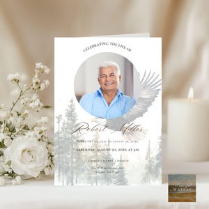 May include: A memorial card with a photo of a smiling man in a blue shirt, with an eagle illustration. The text reads "Celebrating the Life of Robert Miller" and includes dates, time, and location details.