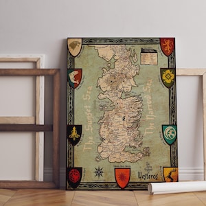 May include: A framed map of Westeros, featuring detailed geographical features and labeled locations. The map is bordered by decorative shields and text, with a vintage aesthetic. The color palette includes shades of green, brown, and beige.