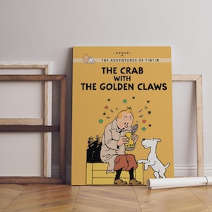May include: A framed poster of "The Crab with the Golden Claws" from The Adventures of Tintin. The poster features a cartoon illustration of Tintin, his dog Snowy, and a can. The background is yellow with black text.