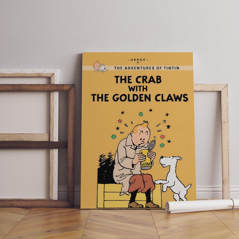 May include: A framed poster of "The Crab with the Golden Claws" from The Adventures of Tintin. The poster features a cartoon illustration of Tintin, his dog Snowy, and a can. The background is yellow with black text.