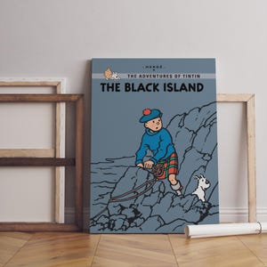 May include: A framed print of "The Black Island" from The Adventures of Tintin. The artwork features Tintin in a blue sweater and kilt, climbing a rocky cliff with his dog Snowy. The title is displayed in bold white letters.