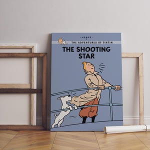 May include: A canvas print of "The Shooting Star" from The Adventures of Tintin. The artwork features Tintin, his dog Snowy, and the title text in bold white letters against a blue background. The print is displayed with a wooden frame.