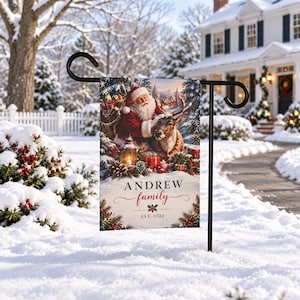 Könnte beinhalten: Eine rechteckige Gartenflagge an einem schwarzen Metallständer mit einer Illustration von Santa Claus, einem Rentier, einer Laterne und Geschenken in einem verschneiten Wald. Der Text lautet ANDREW family EST. 2024 mit einem kleinen Stechpalmen-Symbol.