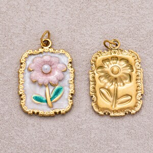 Charm rectangular de acero inoxidable con revestimiento PVD dorado y forma de flor de margarita rosa perlada.