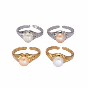 May include: Four open-band rings featuring a single round pearl set in a textured metal frame. Two rings are silver-toned with white and peach pearls, and two are gold-toned with peach and white pearls, all with an adjustable open back.
