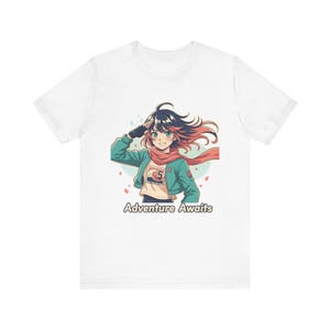 Może przedstawiać: Biała koszulka z ilustracją w stylu anime przedstawiającą dziewczynę z czarnymi i różowymi włosami, w turkusowej kurtce i czerwonym szaliku. Tekst "Adventure Awaits" jest wydrukowany poniżej. Projekt zawiera kwiatowe akcenty.
