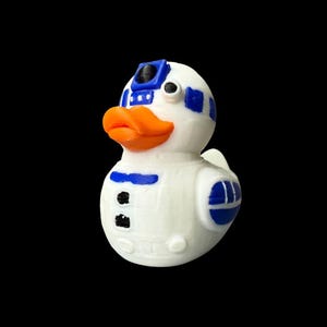 May include: A white rubber duck with blue and black accents, and an orange beak. The duck is designed to resemble the Star Wars character R2-D2. The duck has a black eye and a blue and black head.