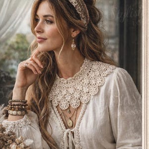 Op de afbeelding: Een vrouw draagt een crèmekleurige Victoriaanse kanten kraag, onderdeel van een PDF-patroon. De afbeelding bevat de tekst "Crochet Victorian Lace Collar Pattern" en "PDF DOWNLOAD". De vrouw draagt ook sieraden en een haarband.