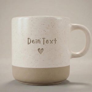 Pode incluir: Caneca de cerâmica creme com acabamento salpicado e base bege. A caneca apresenta o texto gravado "Dein Text" acima de um pequeno símbolo de coração. A alça é de cor creme.