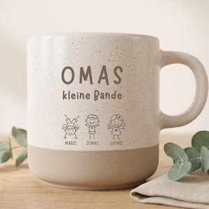 Könnte beinhalten: Ein gesprenkelter, cremefarbener und beiger Keramikbecher mit dem braunen Schriftzug OMAS kleine Bande über drei Strichzeichnungen von Kindern, die mit Marie, Jonas und Leonie beschriftet sind. Der Becher hat einen glatten Henkel.