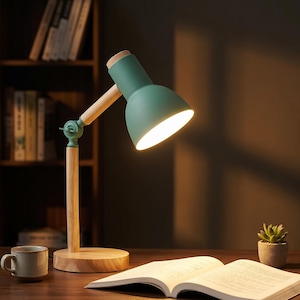 May include: A green and wood desk lamp with a bright light. The lamp has a wooden base and arm, with a green lampshade. A book, a mug, and a small potted plant are on the desk.